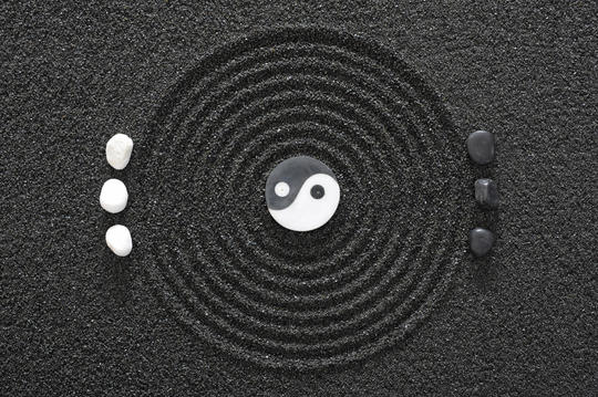Yin og yang symbol med ringer rundt og små steiner på hver side av den ytterste sirkelen.