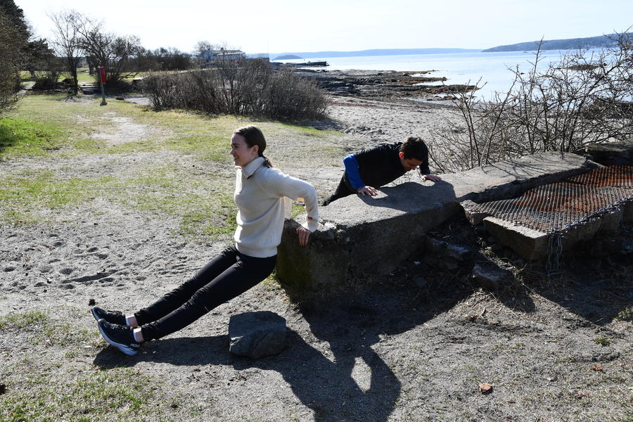 Mann og kvinne tar pushups mot en lang stein.