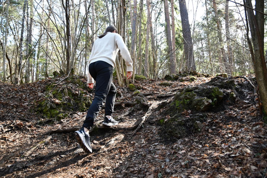En kvinne går opp en bakke i skogen.